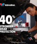 Valvoline Advanced Full Synthetic 0W-20 motor oil, 5 qt bottle on shelf in auto shop with mechanic under hood