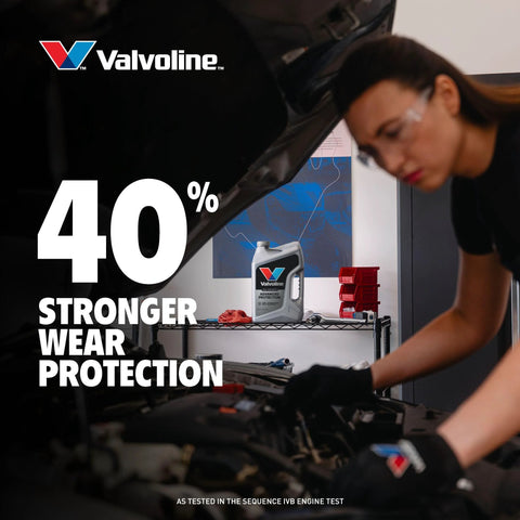 Valvoline Advanced Full Synthetic 0W-20 motor oil, 5 qt bottle on shelf in auto shop with mechanic under hood