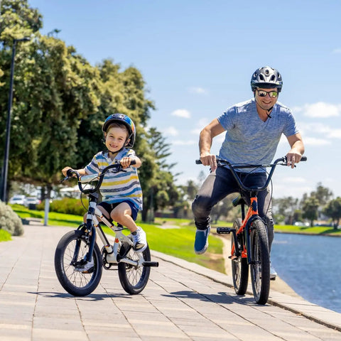 Father and son cycling by a lake on 20 inch bikes, showcasing Bombproof 20 Inch Bike Inner Tube with 32mm Schrader Valve.