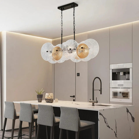 Stylish kitchen with hanging lights, featuring black metal and glass design, over marble island with chairs.