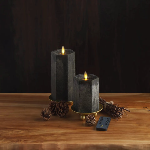 Hexagon Flameless Moving Flame Pillar Candles Set Of 2 in chalky black finish on wooden table with remote and fall decor.