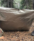 Insulated Tarp Survival Blanket For Camping And Emergency Prep Reusable Heavy Duty Thermal Shield set up in forest.