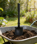 Folding Shovel With Compass Three In One Survival Shovel for Camping and Hiking in a wheelbarrow filled with soil outdoors