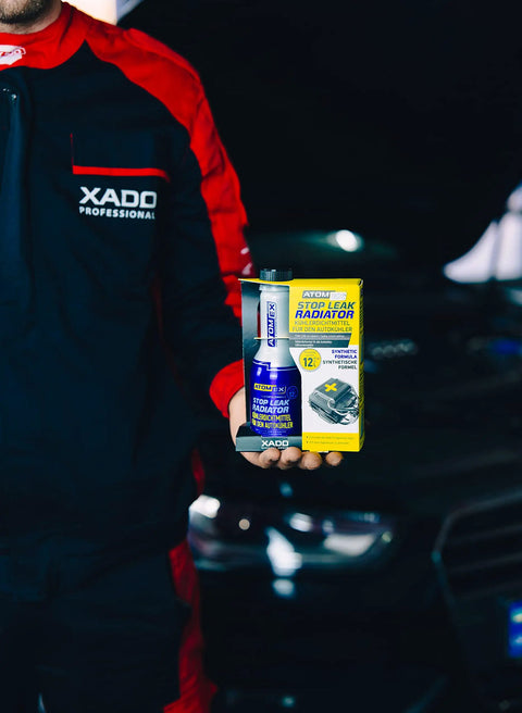 Mechanic holding Stop Leak Radiator Coolant Additive For Cars 250 ml bottle and box in front of car engine