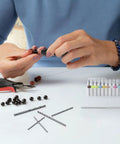 Person using Pro Grade 61 Piece Pin Vise Drill Set With 50 Micro Twist Bits for jewelry making with beads on a table