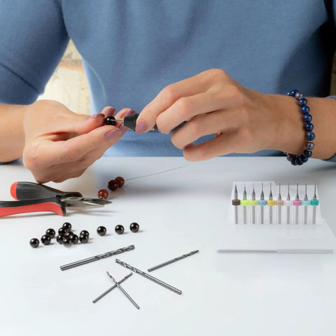 Person using Pro Grade 61 Piece Pin Vise Drill Set With 50 Micro Twist Bits for jewelry making with beads on a table