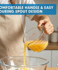 Person pouring liquid into bowl using Must Have Glass Measuring Cups Set With Lids, 4 Piece Borosilicate Kitchen Measuring Cups In 5 Oz, 1 Cup, 2 Cup, And 4 Cup Sizes, Microwave Freezer And Oven Safe, Durable Clear Glass For Baking Cooking And Mixing.