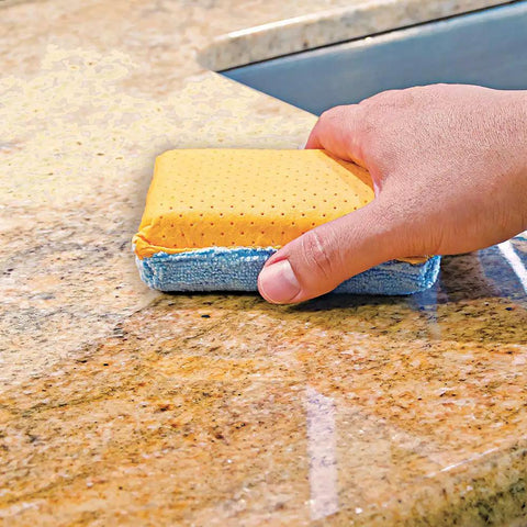 Hand using Chamois And Microfiber Cleaning And Polishing Pad For Countertops And Sinks 4 Inch By 1.75 Inch on stone surface