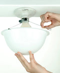 Hands installing ceiling light cover that hides exposed bulbs in seconds, clip-on fit for most bulbs and fixtures, sleek modern design