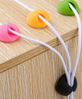 Colorful cable organizer clips maintaining wires on desk edge, illustrating 6 Pack Desk Cable Organizer Clips For Wire Management Adhesive Cord Holders Keep USB Charging Cables Neat And Accessible Office Desktop Organization For Home School And Work