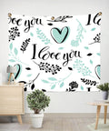 Wall tapestry with 'I love you' message, teal heart and floral design, decorated with brass fasteners in a modern room setting.