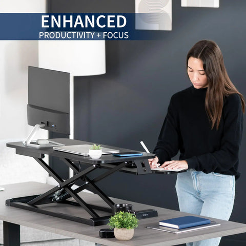 Person using 32 Inch Desk Converter K Series Sit To Stand Riser With Dual Monitor And Laptop Workspace Height Adjustable Standing Desk Attachment Wide Keyboard Tray Black DESK V000K in an office setting