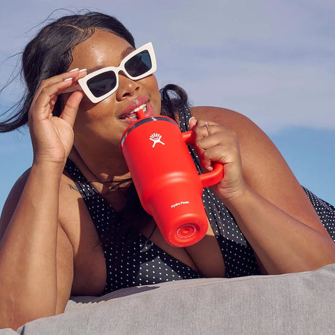 On The Fly 40 Oz Stainless Steel Travel Tumbler With Comfort Grip Handle And Leak Proof Straw Lid used at beach, woman sipping drink.