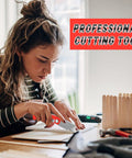 Orange folding utility knife being used to cut white material on a desk; nearby wooden popsicle sticks.
