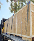Large wooden crates secured with straps on a flatbed truck, using 20 Pack 4 Inch Edge Protectors For Flatbed Trucks With Mesh Carrying Case.