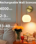 Battery Operated Wall Sconces Set Of Two Rechargeable Gold Milk Glass Wireless Lighting with ambient glow beside roses.