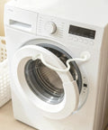 Magnetic Front Load Washer Door Prop And Dryer Vent Holder With Grippy Silicone Base To Keep Your Machines Cracking Open And Smelling Totally Fresh White attached to a washing machine.