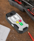 Close-up of 6-in-1 Stud Finder Wall Scanner Metal Detector LCD Display(Grey) on wood table with tools and blueprints.