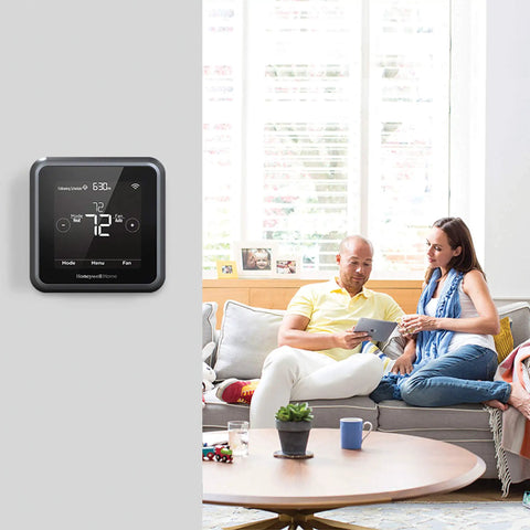 Renewed T5 Plus Smart Thermostat Black with 7 Day Scheduling in living room with couple on sofa.