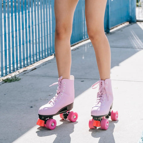 Person wearing pink roller skates outdoors on pavement near blue fence