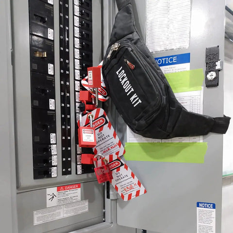 On The Go Lockout Tagout Kit With Clamp-On Circuit Breaker, Group Hasps, Tags, And Two Keyed-Different Padlocks In A Heavy-Duty Nylon Pouch, OSHA Compliant Safety Gear For Universal Multi-Pole Breakers, Black Kit hanging on electrical panel.