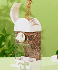 Bird Parent Approved House Shaped Automatic Bird Feeder And Water Dispenser For Parrots And Parakeets Clear large capacity feeder with grains pouring in.