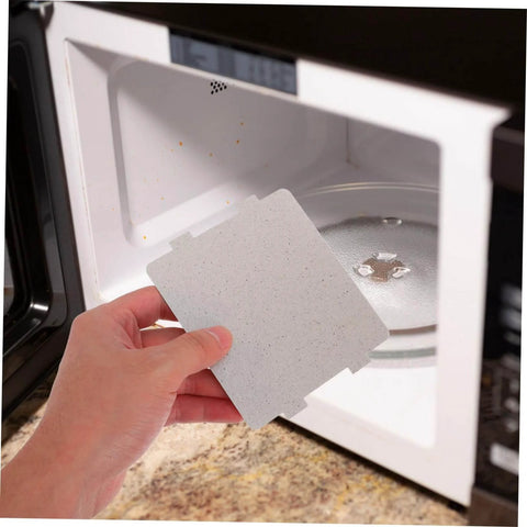 Hand holding Microwave Waveguide Cover Mica Sheet Replacement For Ovens With High Heat Resistance And Insulation Board in front of microwave.