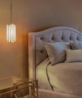Gold Pendant Lighting With White Glass Cylinder For Kitchen Island, Hallway, Foyer, Bedroom, And Dining Room beside a bed