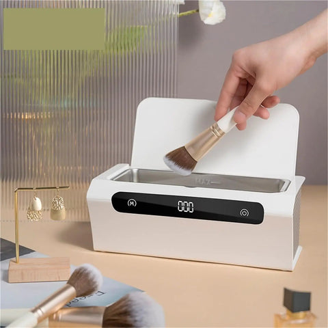 Top Shelf Mini Ultrasonic Cleaner Hella Crisp 500 ML Wash Bath For Rings Glasses Watches Jewelry Razors Headphones And Dental Retainers Portable Clean Machine with a hand inserting a makeup brush.