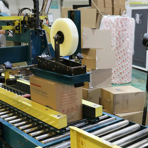 No Frills Clear Packing Tape Two Point Five Mil Thick One Point Eight Eight Inches Wide Six Pack functioning on a packaging machine.