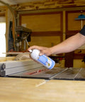 Person applying 6-16-TDL Advanced Dry Lube With Teflon 9.3 Oz Pack Of 6 to a table saw in a woodworking shop