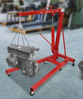 Professional Grade Heavy Duty Two Ton Hydraulic Engine Hoist Folding Cherry Picker Shop Crane lifting an engine in a garage.