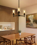 Dining room with Industrial Glass Cylinder Pendant Chandelier in Black, 6 Light Farmhouse Vibe for Dining Room Living Room Kitchen Island, Vintage Metal Ceiling Light Fixture, above wooden table.