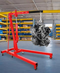Heavy Duty 2 Ton Engine Hoist With Retractable Telescopic Boom and Six Rolling Caster Wheels, lifting an engine in a workshop.