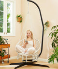 Woman relaxing in Beige Macrame Hammock Chair With Super Comfy Cloud Cushion in indoor setting, supports up to 330 lbs.
