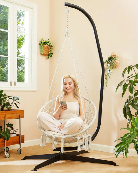 Woman relaxing in Beige Macrame Hammock Chair With Super Comfy Cloud Cushion in indoor setting, supports up to 330 lbs.