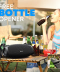 Monster Bass 120W Outdoor Bluetooth Speaker Boombox with IPX6 waterproof build on table with bottles and woman in background.