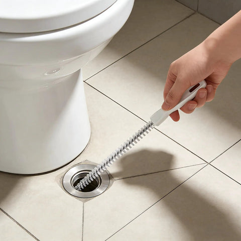Flexible Drain Snake Cleaner Brush That Kicks Out Greasy Gunk Reusable Spiral Hair Removal Tool With Comfort Grip Handles For Sinks Showers And Bathtubs In White in use on a bathroom floor drain.