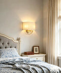 Vintage Linen Fabric Brass Gold Wall Sconce Light for Hallway, Bedroom above a bed in a cozy bedroom setting.