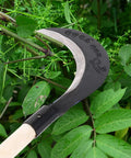 Manganese Steel Long Handle Hand Scythe For Weeding And Lawn Care With Thick Blade Heavy Duty Garden Tool For Outdoor Use shown in greenery