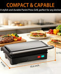 Stainless Steel 1000W Panini Press Grill And Sandwich Maker With Non Stick Plates Removable Drip Tray 3 In 1 Electric Contact Grill Opens 180 Degrees Flat For Burgers Chicken Bacon And More Overheat Protection on kitchen counter.