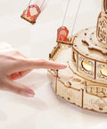 Detail view of 3D Wooden Puzzle Music Box Kit With Led Rotating Swing Ride, showing hand interacting with the intricate wooden design.