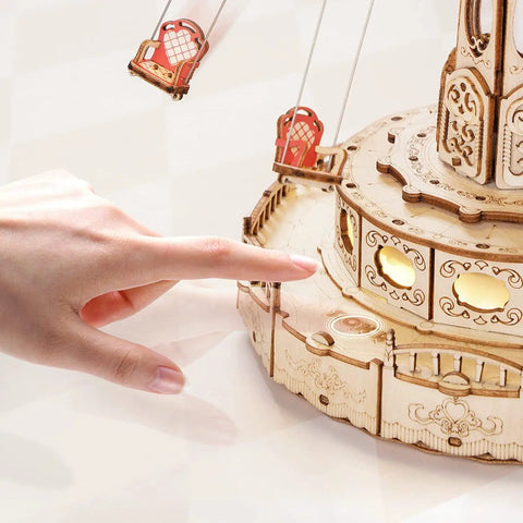 Detail view of 3D Wooden Puzzle Music Box Kit With Led Rotating Swing Ride, showing hand interacting with the intricate wooden design.