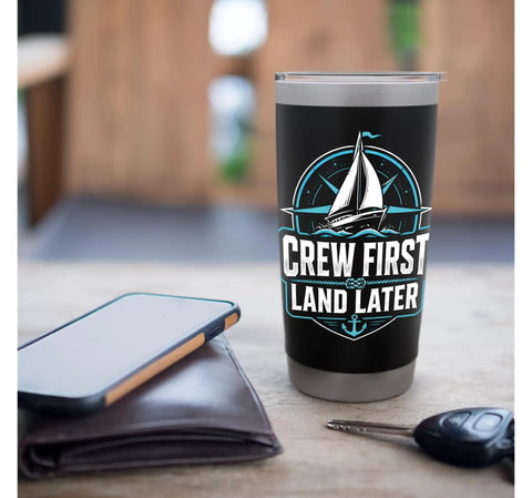 Crew First Land Later Sailboat Stainless Steel Insulated Tumbler for Coastal Sailing and Regatta Days on table with phone