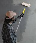 Person using No Sweat Pro Grade Detachable Paint Roller Kit With Telescopic Handle and Three Extra Rods for DIY wall painting.