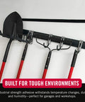 VELCRO Brand heavy-duty tape, black, 1.5-in wide, 16-ft roll mounted above wall tool rack with red-handled garden tools.