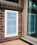 Top Shelf Double Flap Pet Door For Deep Walls Up To 13 Inches installed in a brick wall, featuring secure magnetic vinyl panel.