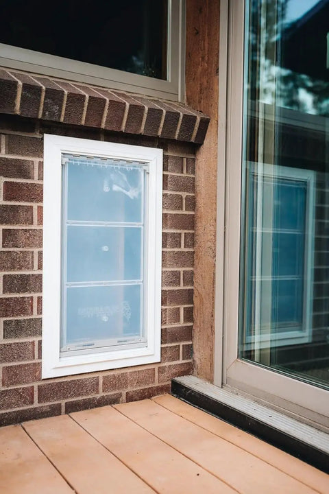 Heavy Duty Wall Mounted Pet Door With Hella Windproof Double Flaps, installed in a brick wall, visible sliding mechanism.