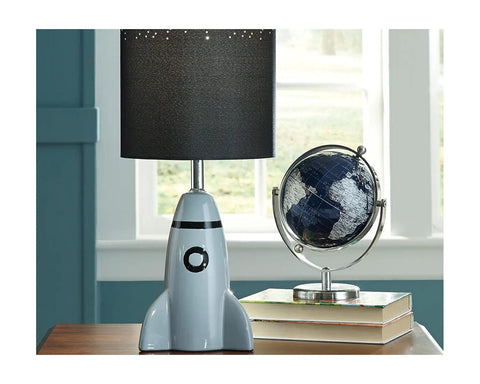 Kids Rocket Table Lamp With Gray Ceramic Base And Fabric Drum Shade beside a globe on a desk