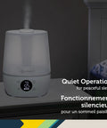 Filter Free Humidifier With Auto Humidity Control And Hygrometer on bedside table, LCD shows humidity levels, white finish.